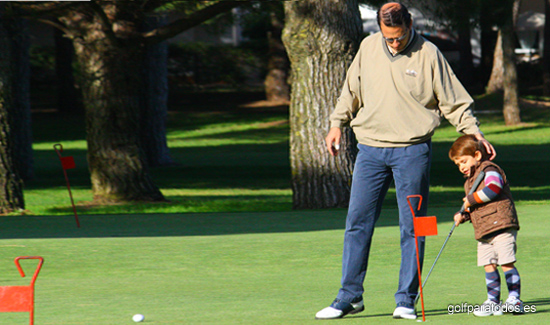 Imagen de un padre y su pequeño hijo en un putting green