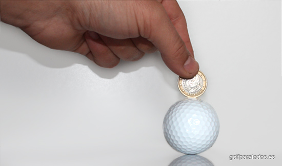 Imagen de una bola de golf y una mano con un euro